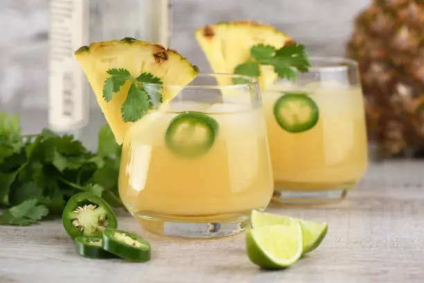 Tequila cocktail with pineapple juice, jalapeno  slices and cilantro, cooled with ice