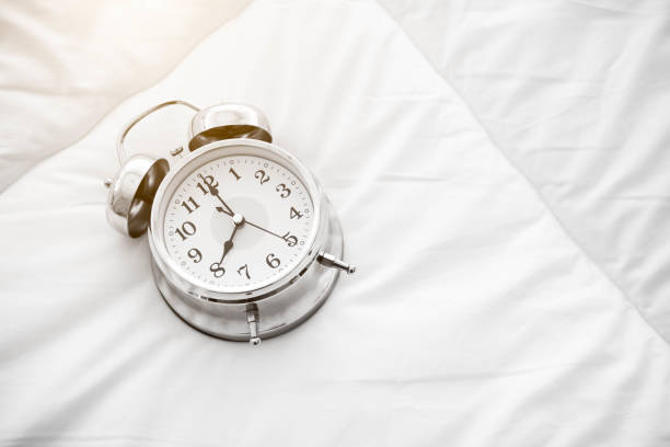 istock Ringing alarm clock on white bed sheet. Top view of object. 8 o clock setting up 1155652750