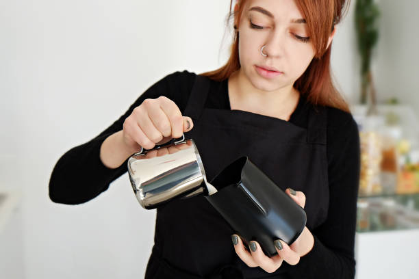 istock Redheaded young woman working in coffee shop prepearing a drink. 1155654701