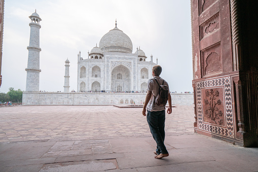 Young man contemplating the famous Taj Mahal at sunset, Agra, India.\nPeople travel Asia concept