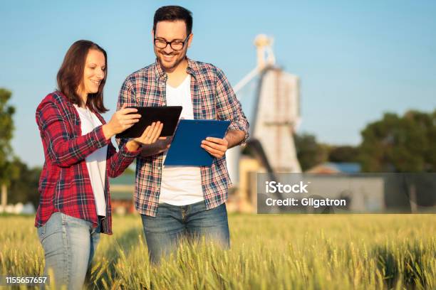 Two Smiling Happy Young Male And Female Agronomists Or Farmers Talking In A Wheat Field Stock Photo - Download Image Now