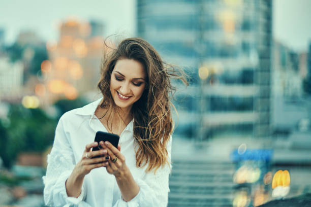 istock Young woman over cityscape holding a smart phone texting 1155661338