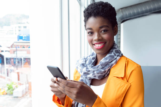 istock Businesswoman using mobile phone near window in office 1155662631