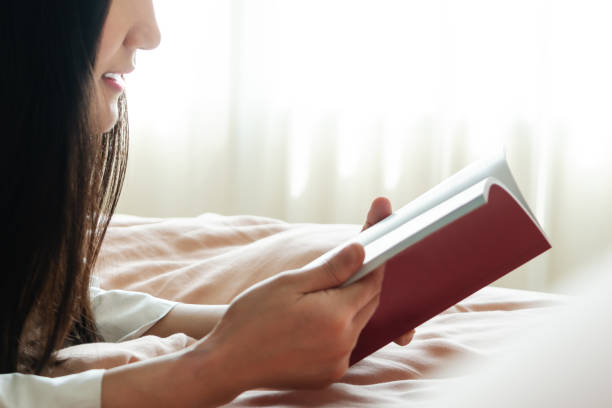 istock world book day, woman lay on bed reading the blank book 1155662937