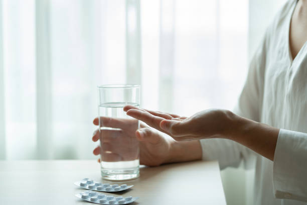 うつ病の女性は、水、ヘルスケア、薬の回復の概念のガラスで薬を手に持つ - water women glass healthy eating ストックフォトと画像