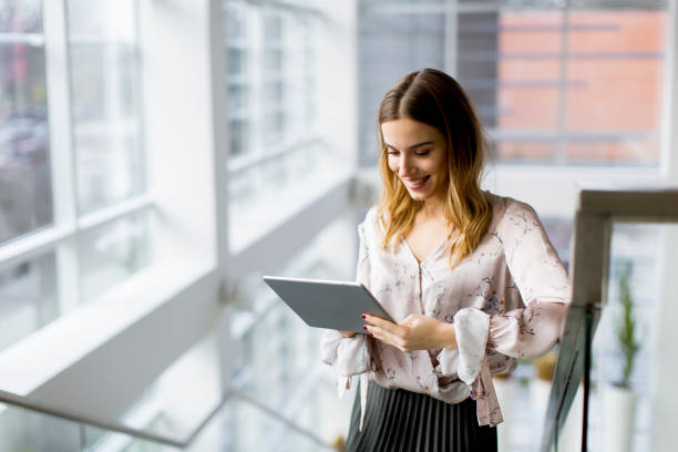 istock Attractive businesswoman using a digital tablet while standing on the stairs in the office 1155664224