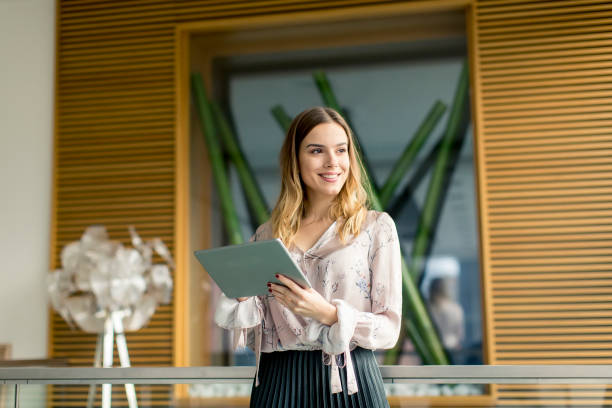 istock Attractive businesswoman using a digital tablet while standing in the office 1155664229