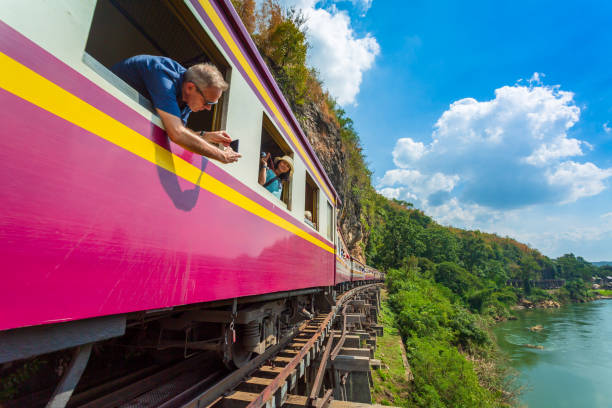 : 桂ノイバイ川の美しい景色の写真を撮る電車の中で多くの観光客と死の鉄道として知られている第二次世界大戦の歴史的な鉄道、。 - kanchanaburi province ストックフォトと画像