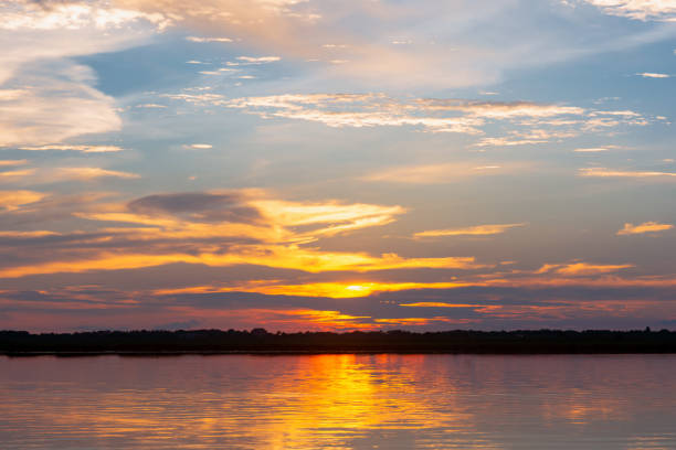 istock Sunset reflection lagoon. beautiful sunset behind the clouds and blue sky above the over lagoon landscape background. dramatic sky with cloud at sunset 1155666838