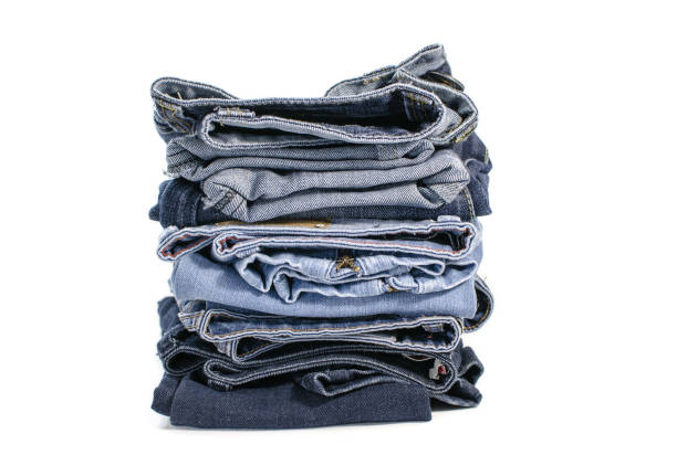istock Denim blue jeans stack on white background. Clothes, fashion, charity 1155669743