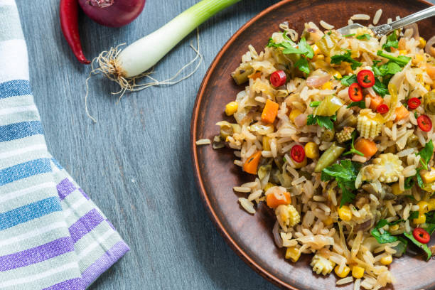 istock Veggie fried rice with cabbage, carrots, corn, onion, beans and pepper with chopped parsley and chili in a plate on a wooden table, a rustic style 1155671737