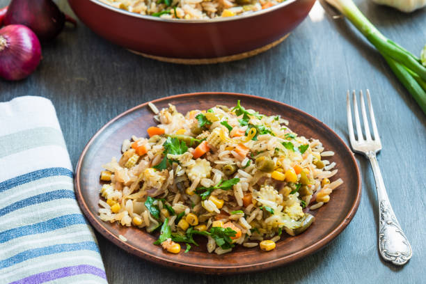 istock Veggie fried rice with cabbage, carrots, corn, onion, beans and pepper with chopped parsley and chili in a plate on a wooden table, a rustic style 1155671913