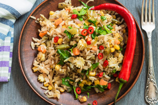 istock Veggie fried rice with cabbage, carrots, corn, onion, beans and pepper with chopped parsley and chili in a plate on a wooden table, a rustic style 1155672059