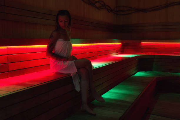 Tattoed girl in white towel relaxing in sauna