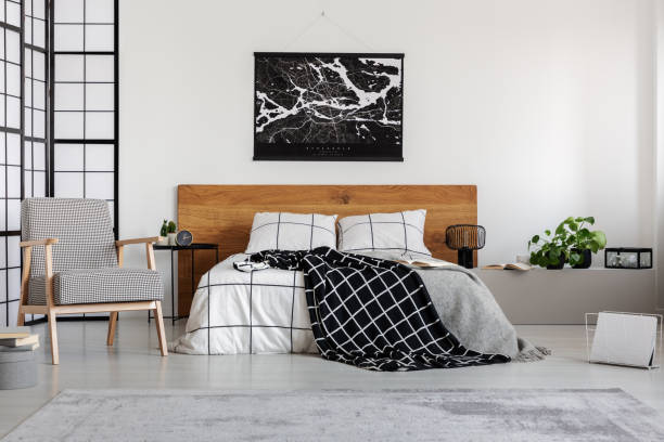 istock Black map on white wall above wooden headboard in simple bedroom interior 1155675317