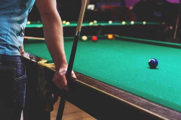 istock the guy is standing with a cue leaning on the pool table, retro toned 1155678668