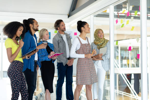 istock Business people discussing over sticky notes on glass wall in a modern office 1155679175