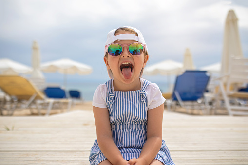 A little girl in a swimsuit runs on a sandy beach in Georgia and plays with the waves