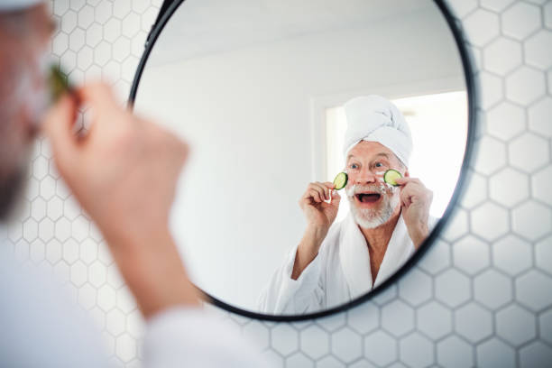 um homem sênior com o pepino nos olhos dentro em casa. copie o espaço. - human skin sparse washing face human face - fotografias e filmes do acervo