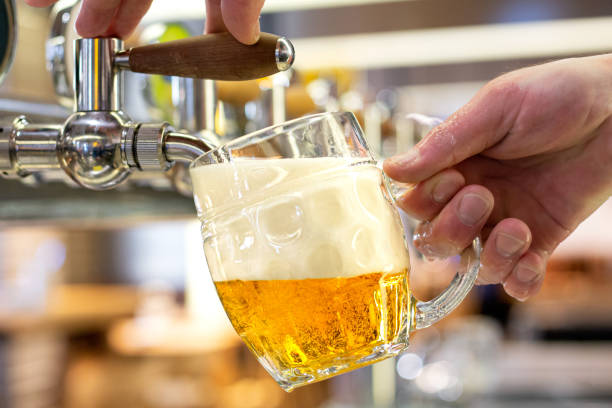 istock A man pouring draft lager beer into a dimpled glass mug  in a modern pub. 1155680815