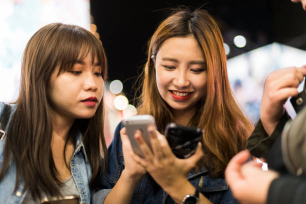 istock Young woman using multiple smart phones out at night 1155683492