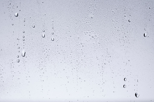 Half opened front car door misted window covered with a cold rain drops with a rocky mountains range and heavy stormy clouds.