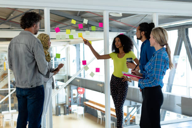 istock Business people discussing over sticky notes on glass wall in a modern office 1155685650