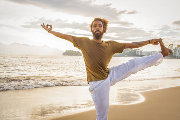 istock man doing yoga on the beach 1155688053