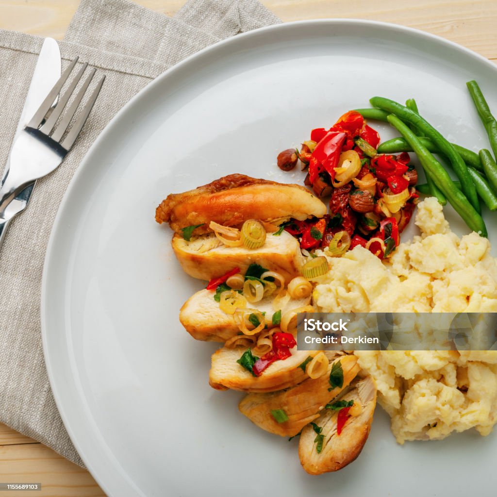 Chicken fillet with mashed potato Homemade tasty chicken fillet with green beans, mashed potato and vegetable sauce on a round white plate. Traditional healthy meal. Top view, above shot. Above Stock Photo