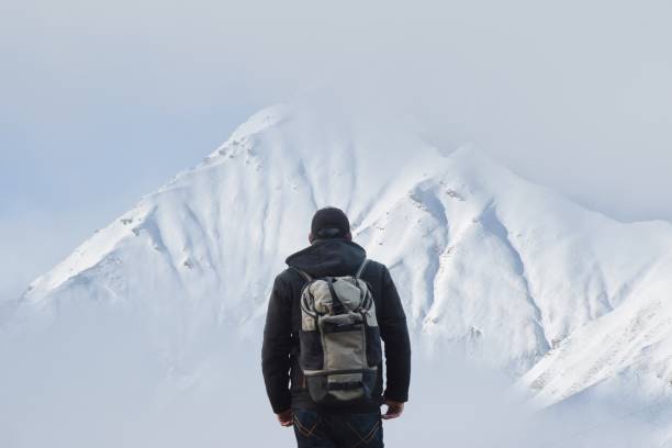 istock Rear View Of Man With Backpack Looking At Snowcapped Mountain Against Sky 1155689132