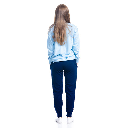 Woman in blue sweatpants sport style casual standing looking on white background isolation, back view