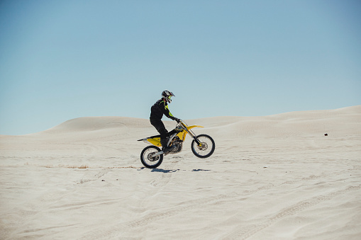 Motociclista tirando de una Caballito en la arena photo