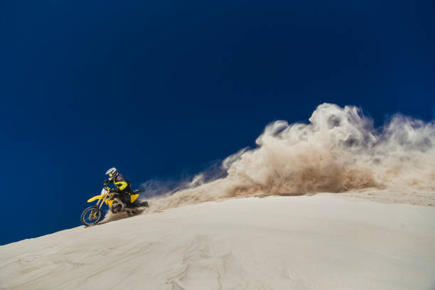 Motorcyclist riding his bike across sand dunes.