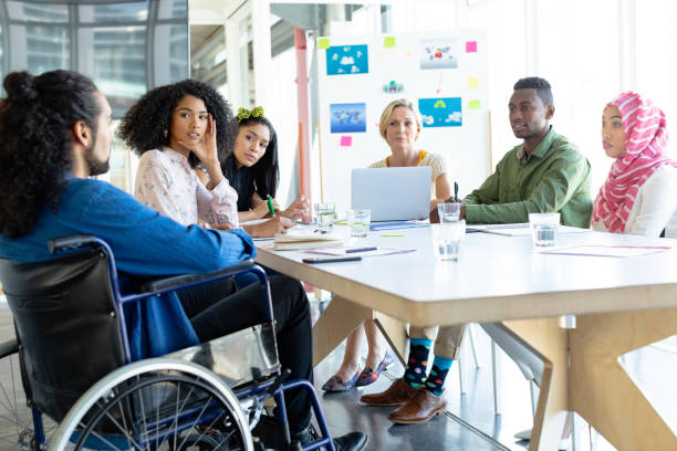 Business people discussing with each other in meeting at conference room in a modern office Front view of diverse business people discussing with each other in meeting at conference room in a modern office persons with disabilities photos stock pictures, royalty-free photos & images