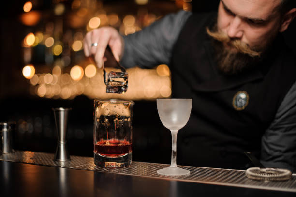 istock Bartender putting an ice cube to the measuring glass cup 1155693275
