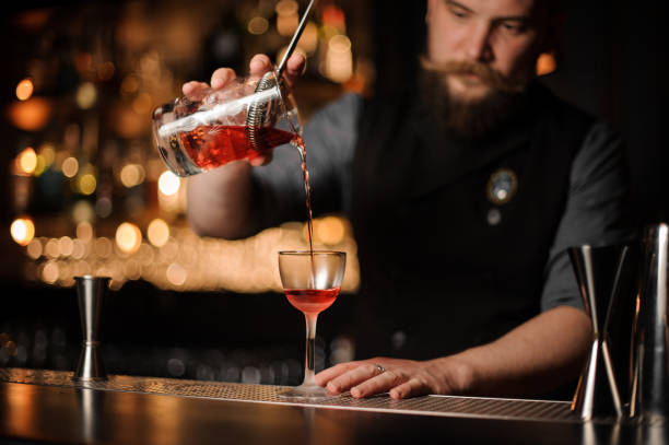 istock Bartender pouring a red cocktail from the measuring glass cup 1155693326