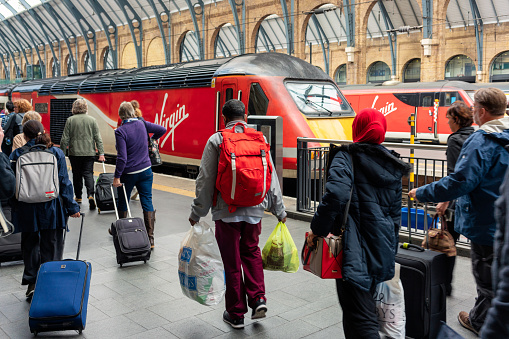 London, UK - Passengers carrying luggage along a platform in King's Cross station, to board a Virgin intercity train.