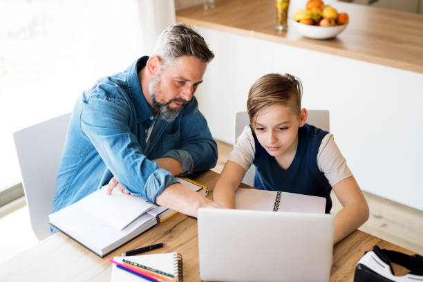 istock Mature father with small son sitting at table indoors, using laptop. 1155700899