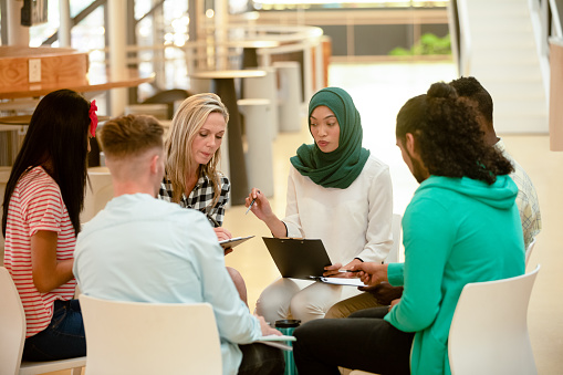 Front view of diverse business people sitting together and having a group discussion in a modern office