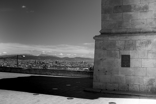 Stunning view of Barcelona, shot taken a few steps from the watchtower of the castle located on the Montjuic hill,  horizontal composition, black and white photography, copy-space.
