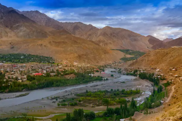 Indus river turns around Kargil City valley with Himalayan mountains and blue cloudy sky in background, Leh, Ladakh, Jammu and Kashmir, India