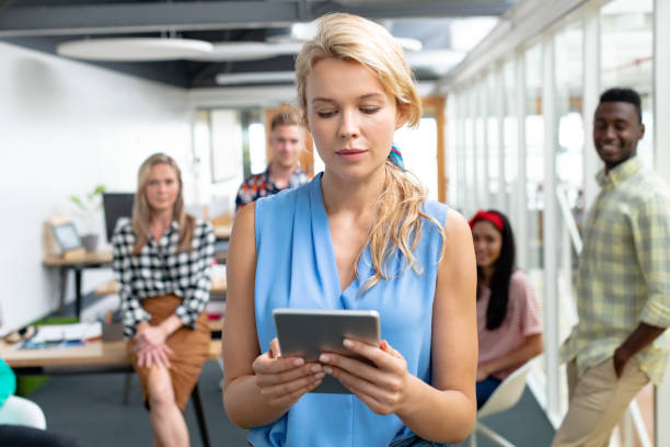 istock Businesswoman using digital tablet while diverse colleagues standing in background at office 1155705416