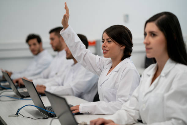 istock Female student at a computer lab lesson raising her arm to ask a question 1155707530