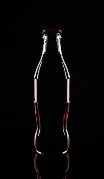 Photo of Glass bottle of soda, isolated on black background