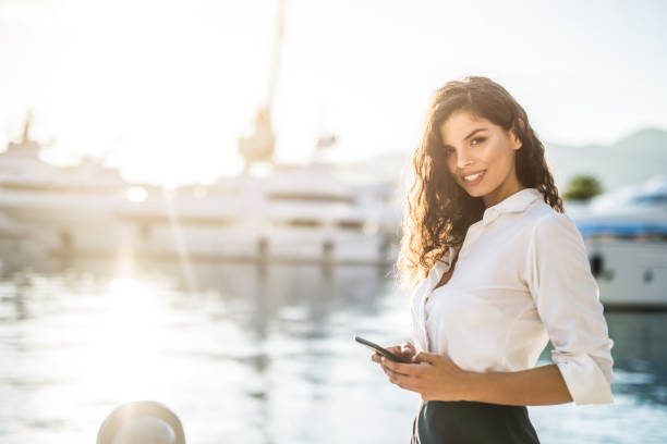 istock Young businesswoman using phone on a harbor. 1155710819