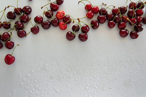 Top view of raw cherries on white background, space for text