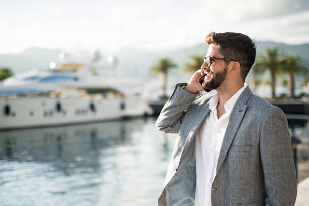 istock Young male entrepreneur having a phone conversation on a harbor. 1155716497
