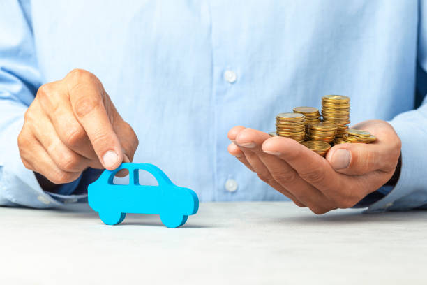 Man in blue shirt is holding car and stack of coins. Concept car purchase, taxes or insurance Man in blue shirt is holding car and stack of coins. Concept car purchase, taxes or insurance. cash for cars stock pictures, royalty-free photos & images