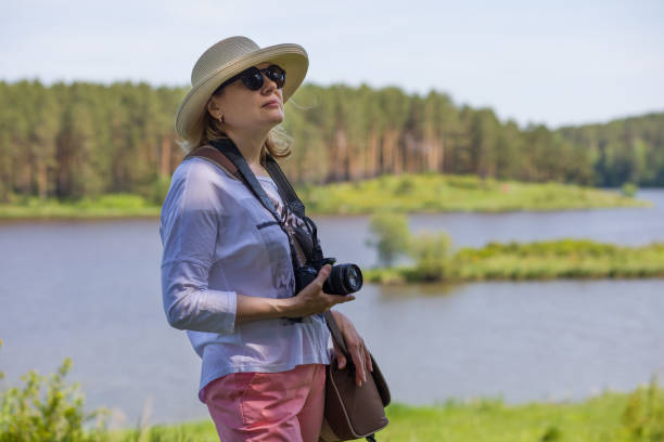 istock An elderly woman with a camera in nature. 1155722509