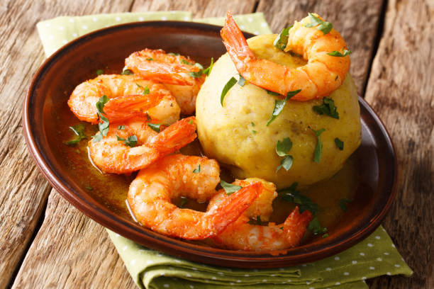 Mofongo mashed plantains, garlic and chicharron served with shrimps and broth close-up on a plate. horizontal, rustic style